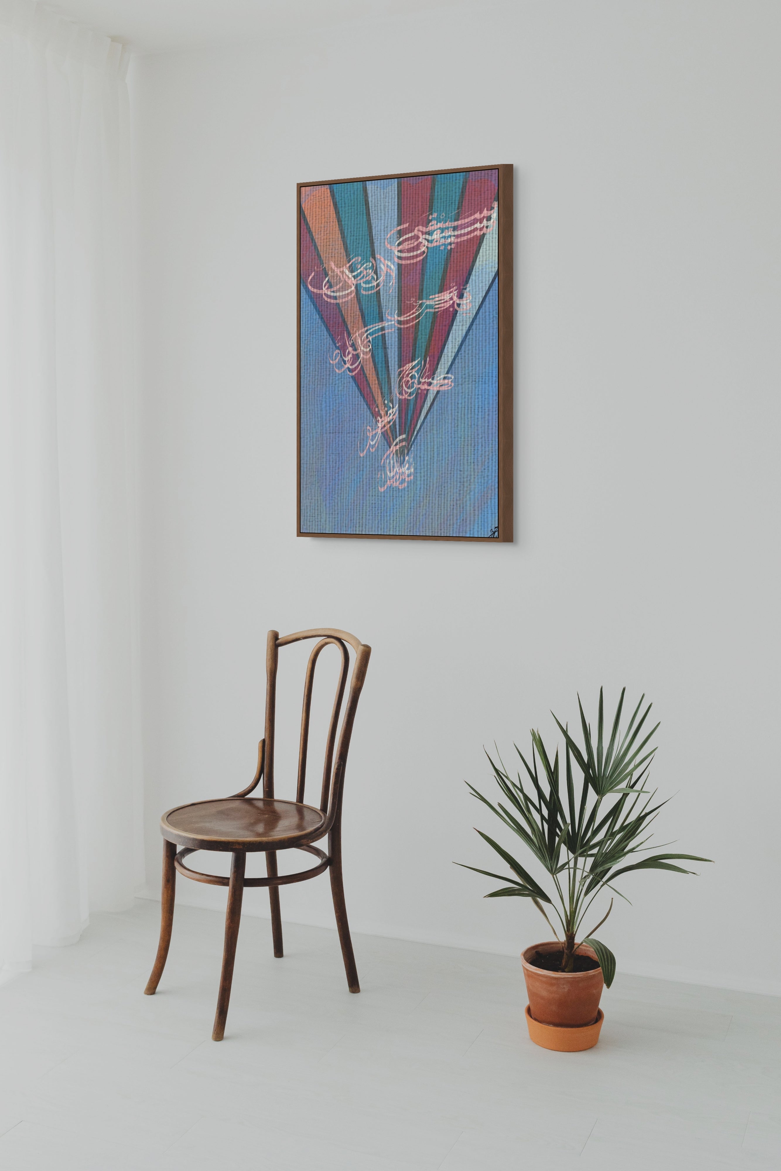 Modern interior featuring a framed Arabic calligraphy artwork on a white wall with a wooden chair and potted plant.