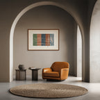 Lebanon art print by ENJZ in a walnut frame, displayed between arches above an amber leather armchair in a warm minimalist interior. Original Arabic poetry by Zein Sourany.